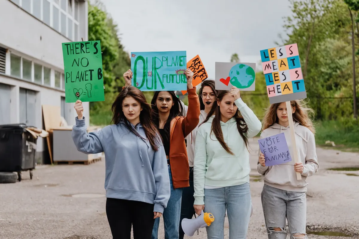 Group of women holding environmental protest signs outdoors advocating for climate action.