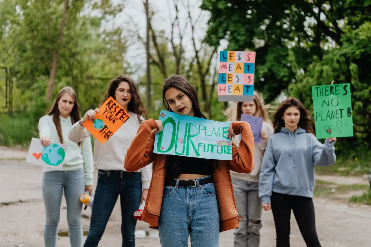 A group of young women protesting for environmental awareness with placards on a street.
