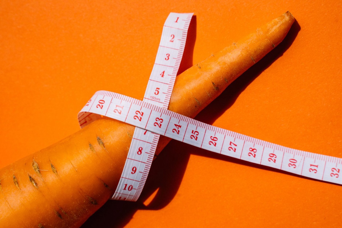 Ruban à mesurer posé à côté d'une pomme verte sur un plan de travail.