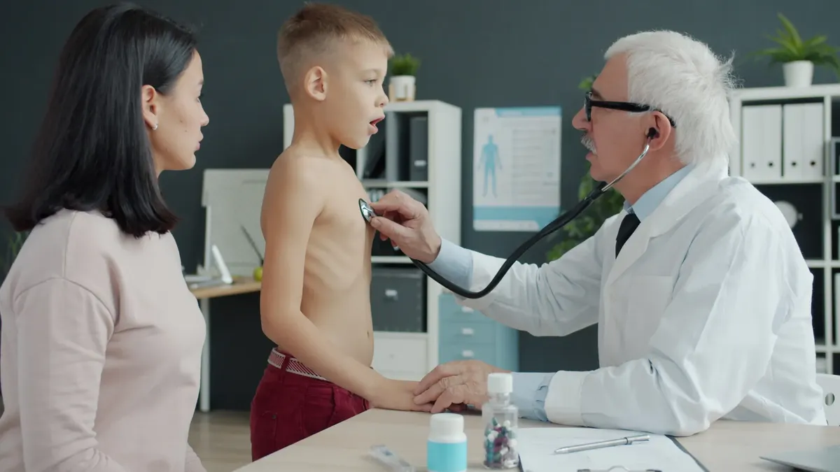 A doctor uses a stethoscope to examine a child in a clinical setting.