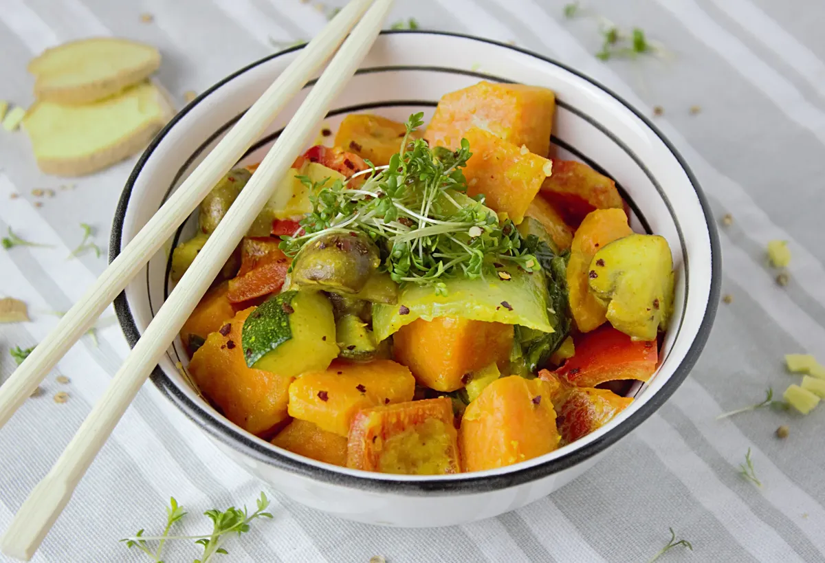 Colorful vegetable stir fry with fresh herbs served in a bowl with chopsticks for a healthy meal.