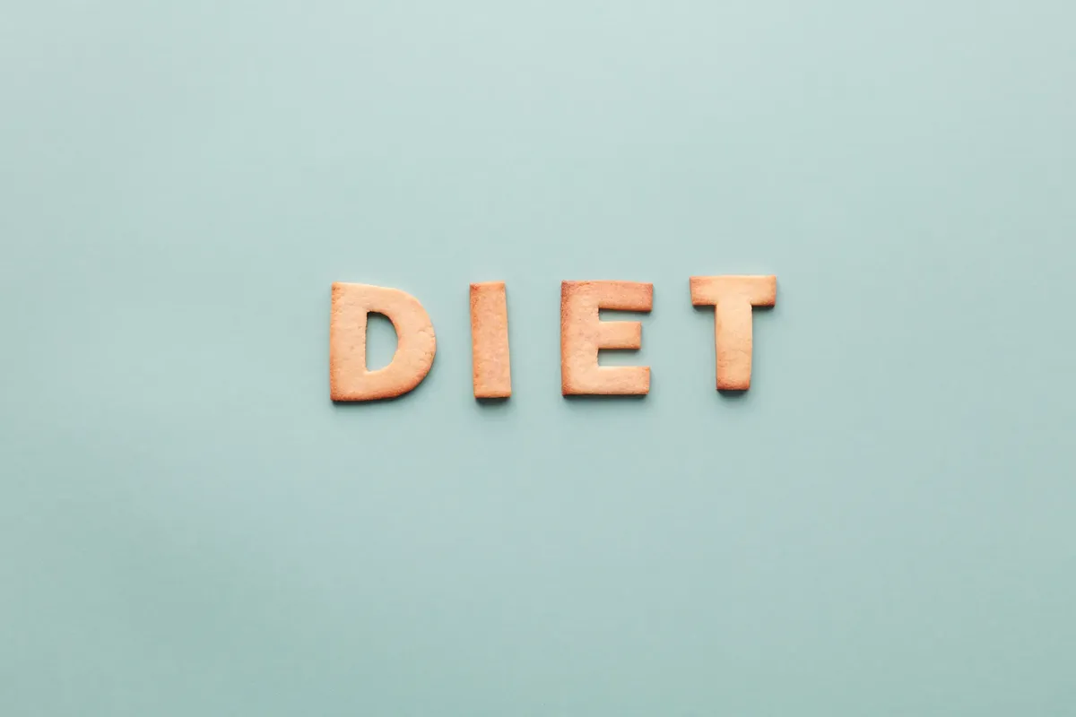 Alphabet cookies spelling 'diet' on a soft turquoise background, shot as a flat lay.